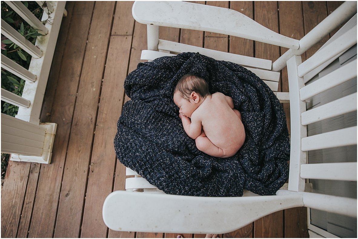 newborn baby sleeping on rocking chair with blue knit blanket