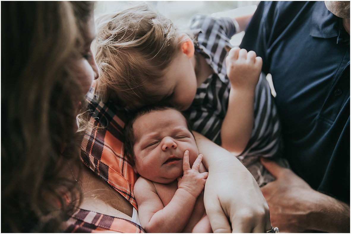 toddler snuggling his newborn brother durning family photo session