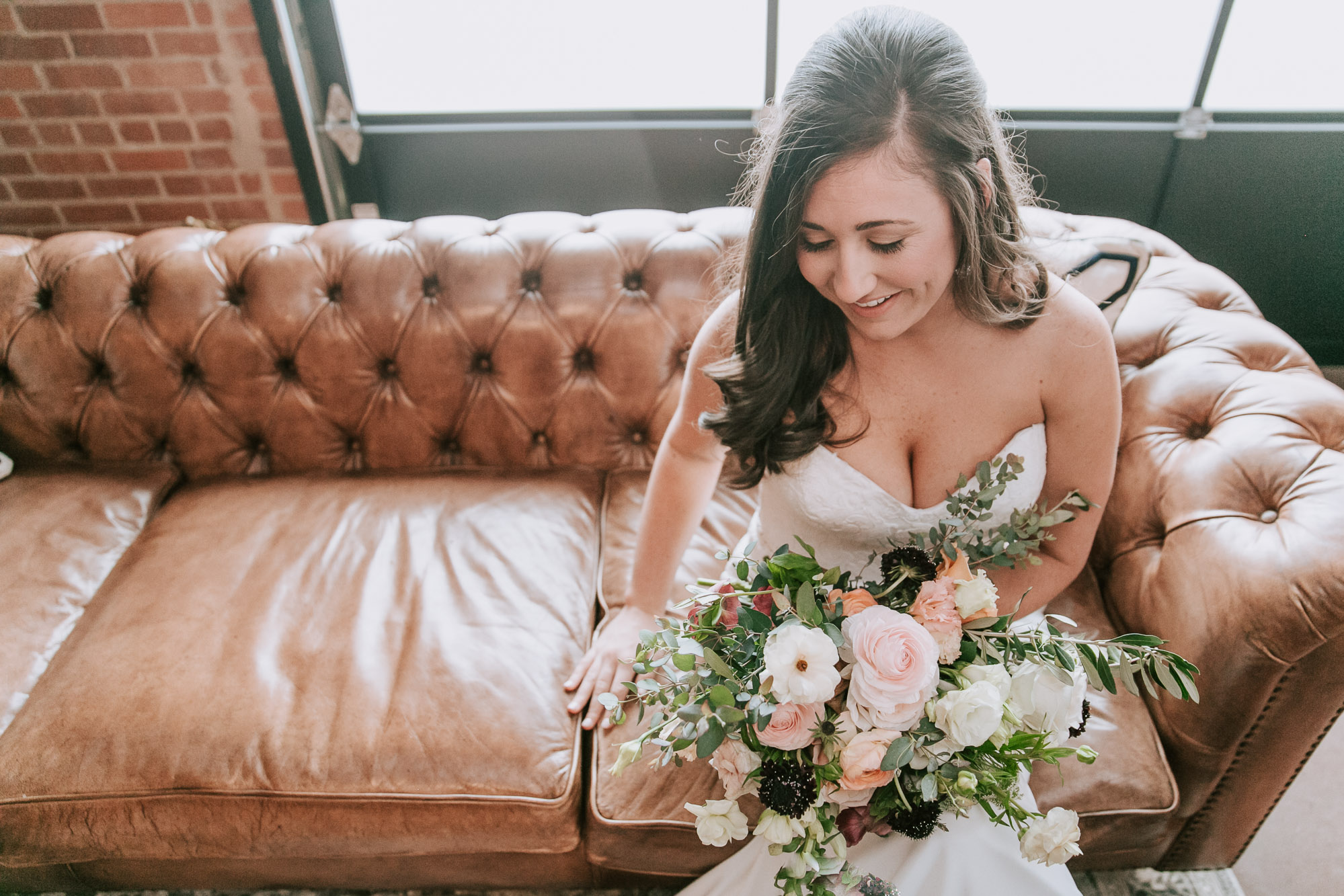 bride sits on couch in bridal suite at the cookery