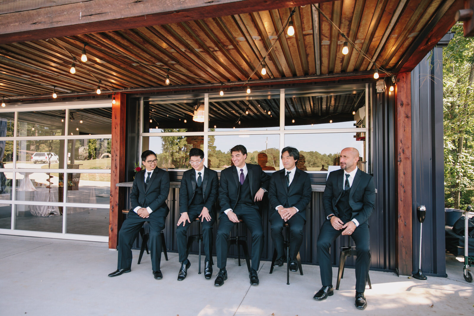 groomsmen sitting at outdoor bar at raleigh wedding venue